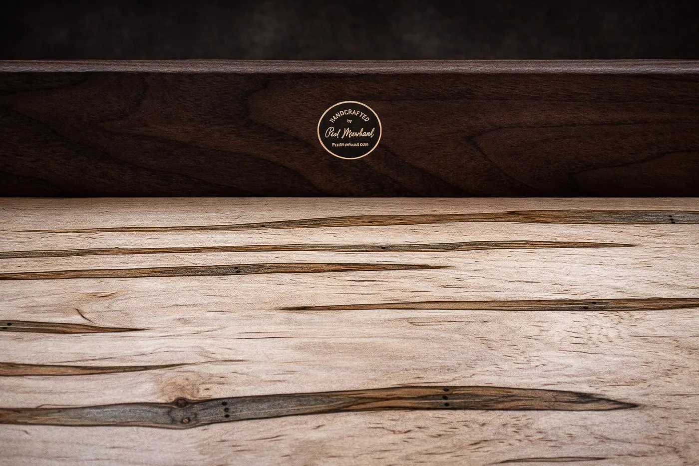 Close detail of ambrosia maple figure, walnut rail, and maker's mark.